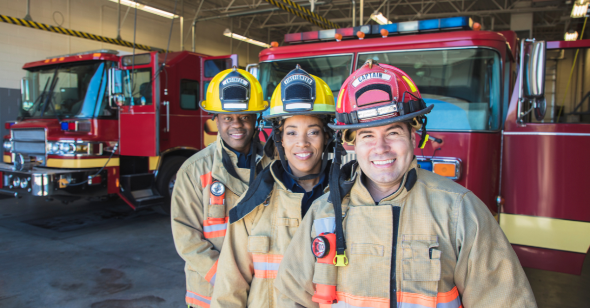 firefighters smiling in a firehouse about their fire department fundraising